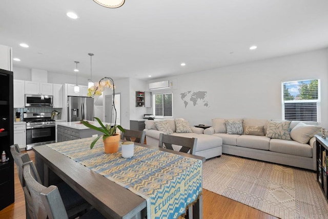 dining room featuring light wood-type flooring and a wall unit AC