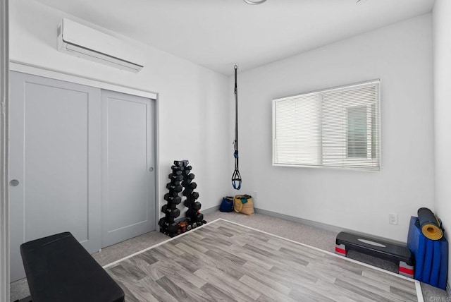 workout area with light hardwood / wood-style flooring and a wall mounted air conditioner