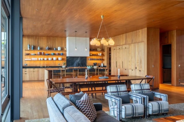 dining room with wood walls, light wood-type flooring, and wooden ceiling