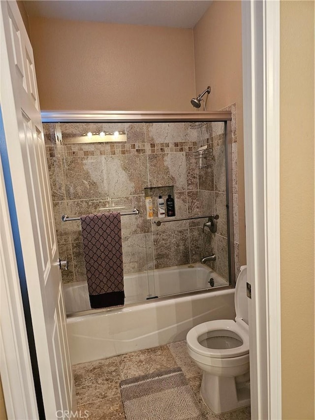 bathroom featuring toilet and combined bath / shower with glass door