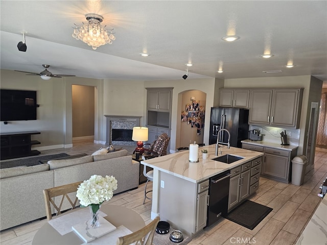 kitchen with a breakfast bar, sink, gray cabinetry, and black appliances