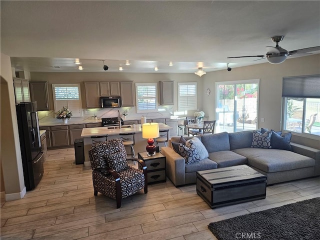 living room with light hardwood / wood-style floors, ceiling fan, and sink