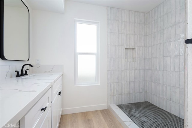 bathroom with a tile shower, vanity, a healthy amount of sunlight, and hardwood / wood-style flooring