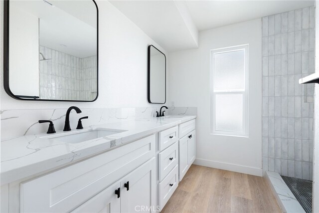 bathroom with hardwood / wood-style floors, vanity, and a tile shower