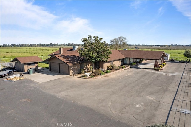 single story home with a garage, a rural view, and an outdoor structure