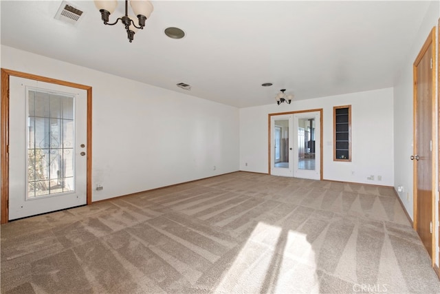 unfurnished room featuring an inviting chandelier, french doors, and carpet floors