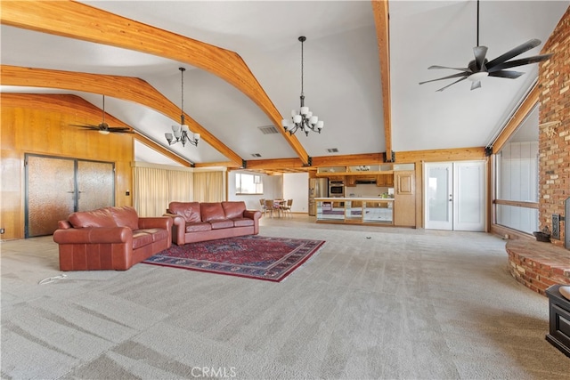 carpeted living room with a fireplace, lofted ceiling with beams, brick wall, and ceiling fan with notable chandelier