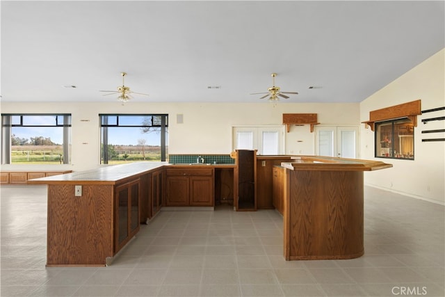 kitchen with sink, ceiling fan, light tile floors, and kitchen peninsula