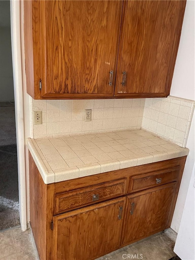 kitchen with light tile patterned floors, tile counters, and decorative backsplash