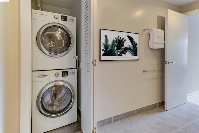 clothes washing area featuring stacked washing maching and dryer and tile flooring