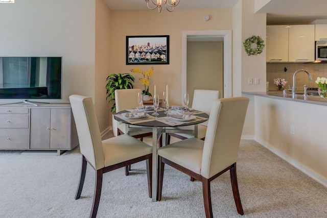 dining room featuring a notable chandelier, light carpet, and sink