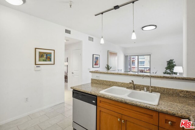 kitchen with sink, decorative light fixtures, light tile patterned floors, light stone countertops, and dishwasher