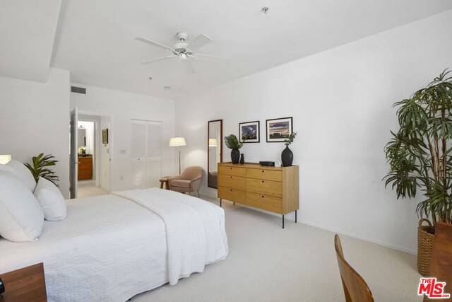 carpeted bedroom with ensuite bathroom and ceiling fan