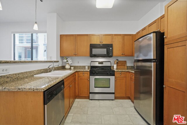 kitchen featuring stainless steel appliances, hanging light fixtures, sink, light stone counters, and light tile patterned floors