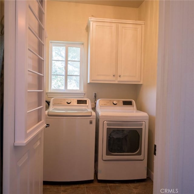 clothes washing area featuring dark tile patterned flooring, cabinets, and independent washer and dryer