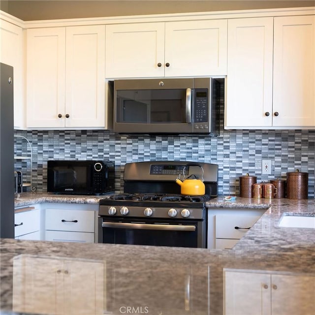 kitchen featuring backsplash, light stone countertops, white cabinetry, and stainless steel appliances