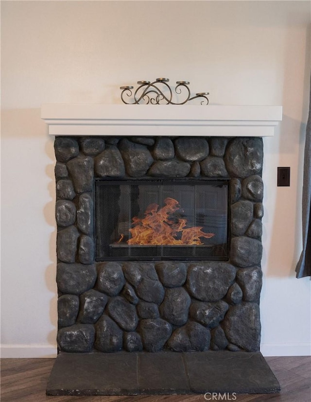 interior details featuring a stone fireplace and wood-type flooring