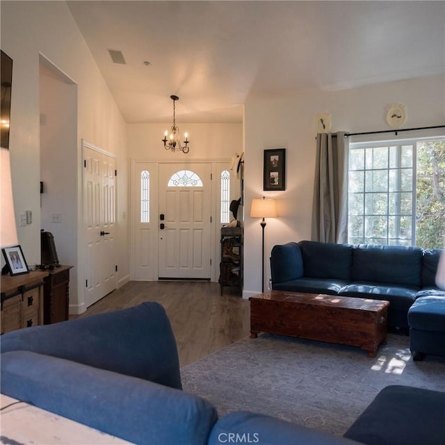 living room with a chandelier, wood-type flooring, and vaulted ceiling