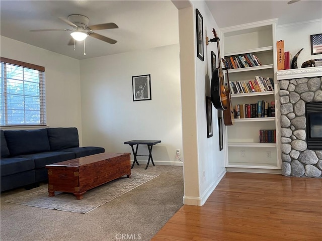 living room featuring a stone fireplace, ceiling fan, and hardwood / wood-style flooring