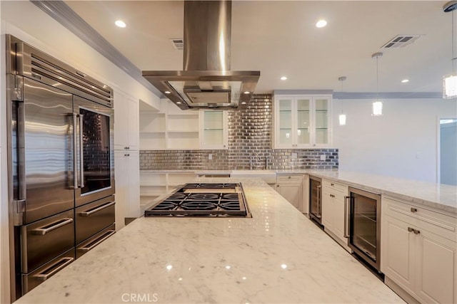 kitchen with light stone countertops, stainless steel appliances, island range hood, pendant lighting, and wine cooler