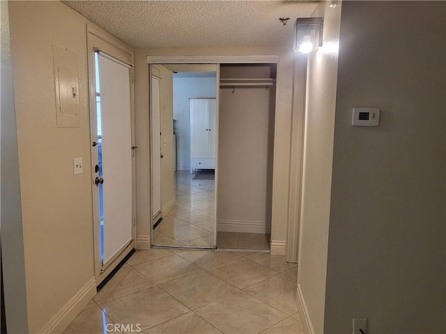 corridor with light tile patterned floors and a textured ceiling