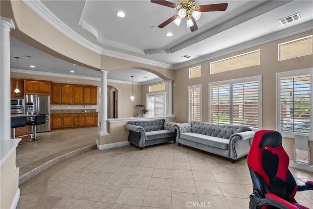 tiled living room featuring decorative columns, ceiling fan, ornamental molding, and a tray ceiling