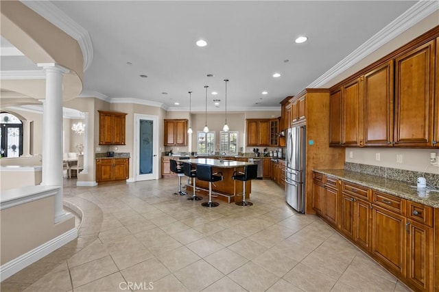 kitchen with stainless steel fridge, ornamental molding, a kitchen island, light stone counters, and a breakfast bar area