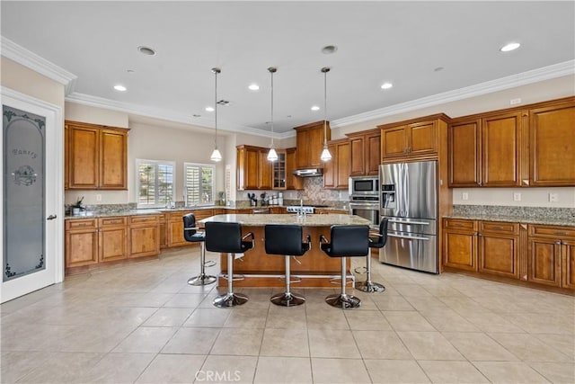 kitchen with appliances with stainless steel finishes, light stone counters, crown molding, a kitchen island, and a breakfast bar area