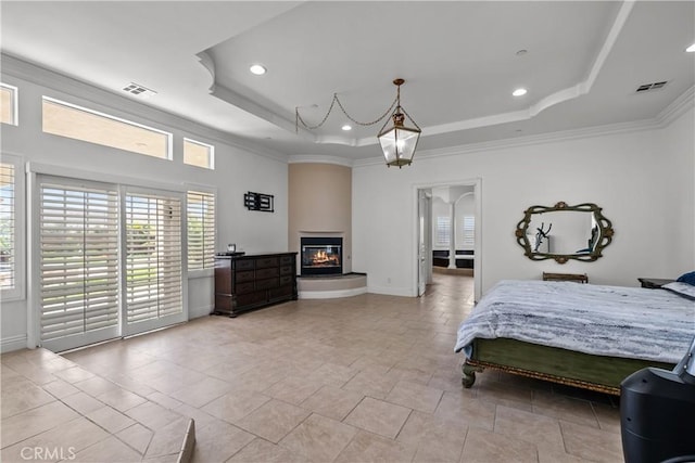 bedroom with a tray ceiling, crown molding, and a fireplace