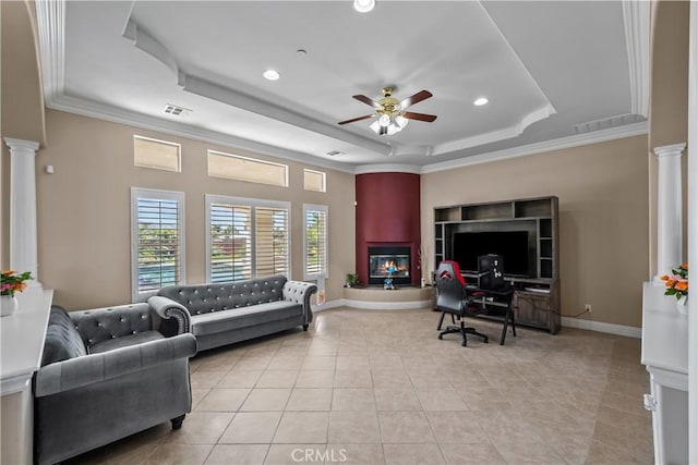 tiled living room featuring a tray ceiling, ceiling fan, crown molding, and decorative columns