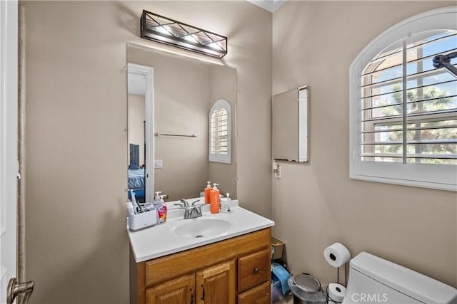 bathroom with plenty of natural light, toilet, and vanity