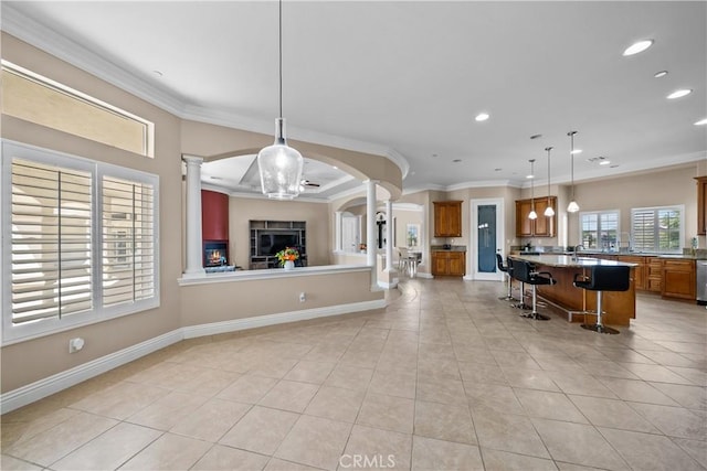 kitchen with pendant lighting, ornamental molding, light tile patterned flooring, a kitchen bar, and kitchen peninsula