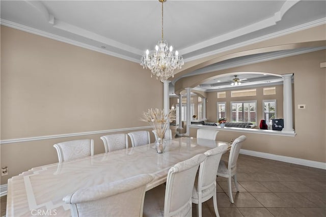 tiled dining space featuring a raised ceiling, ornate columns, ceiling fan with notable chandelier, and ornamental molding