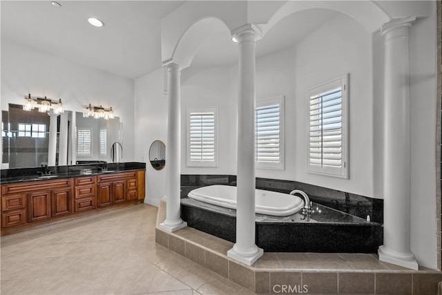 bathroom with tiled bath, tile patterned flooring, and vanity