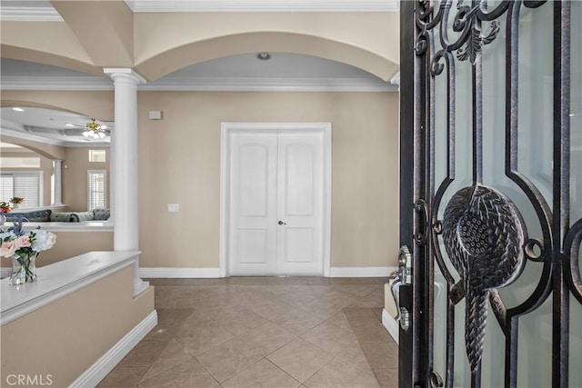 entrance foyer with ceiling fan, ornamental molding, light tile patterned floors, and ornate columns