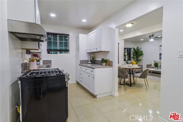 kitchen with ceiling fan, black stove, white cabinetry, and light tile patterned floors