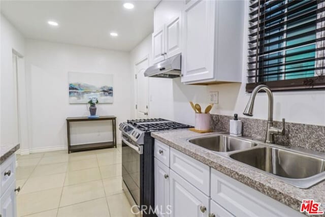 kitchen featuring gas stove, sink, white cabinets, and light tile patterned floors