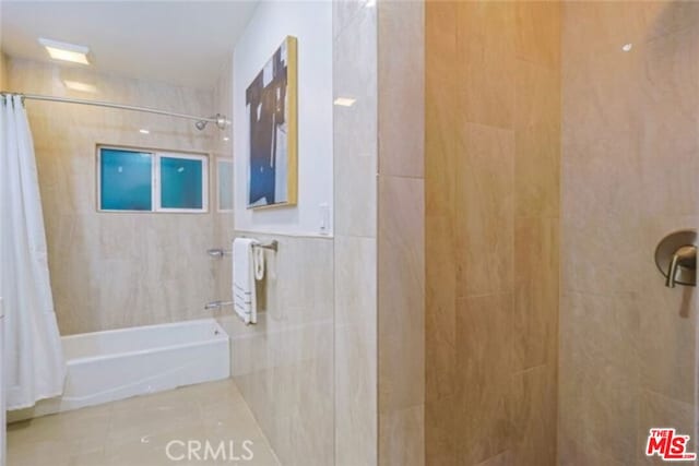 bathroom with tile patterned flooring, shower / bath combo, and tile walls