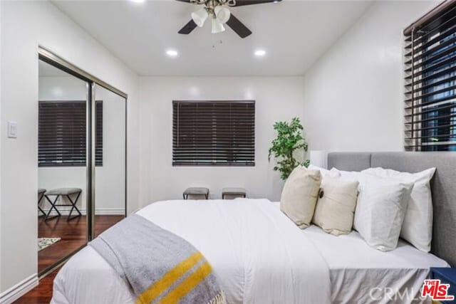 bedroom with a closet, dark wood-type flooring, and ceiling fan