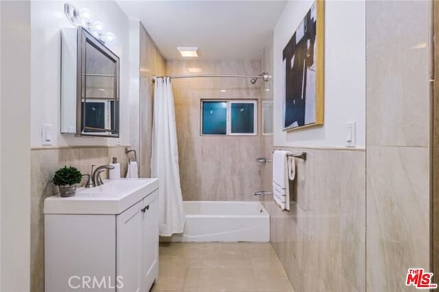 bathroom with tile patterned floors, vanity, shower / tub combo with curtain, and tile walls