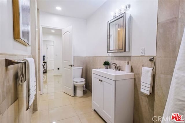 bathroom with tile patterned flooring, vanity, toilet, and tile walls