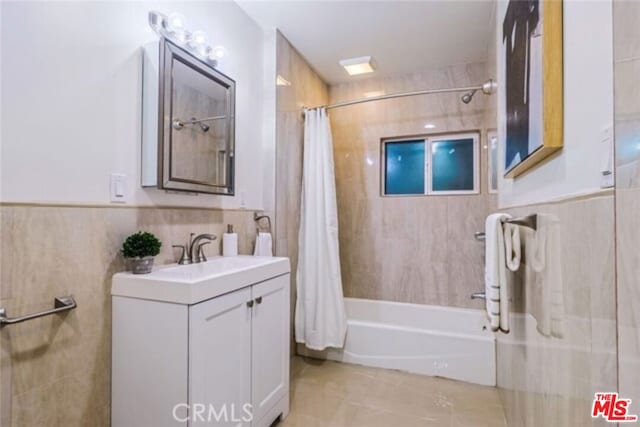 bathroom with shower / tub combo, vanity, and tile walls