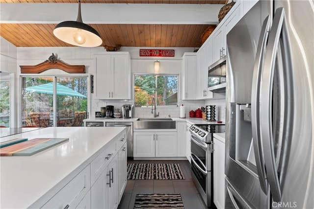 kitchen with stainless steel appliances, a sink, white cabinets, light countertops, and pendant lighting