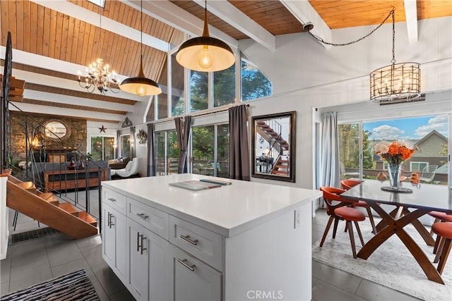 kitchen featuring a notable chandelier, a kitchen island, white cabinets, light countertops, and beam ceiling