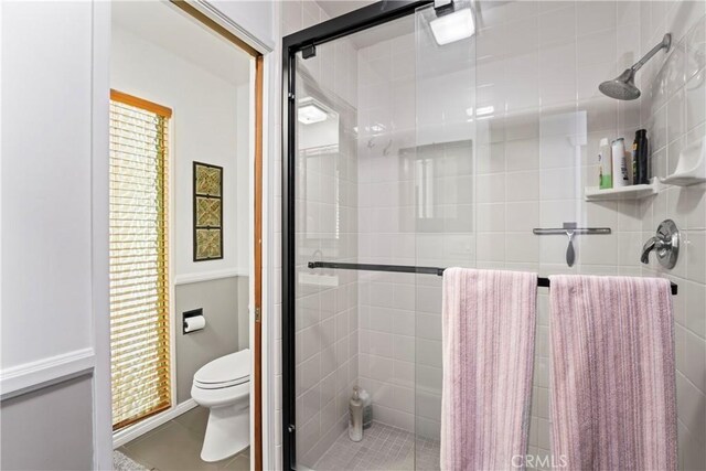 full bath featuring a shower stall and toilet