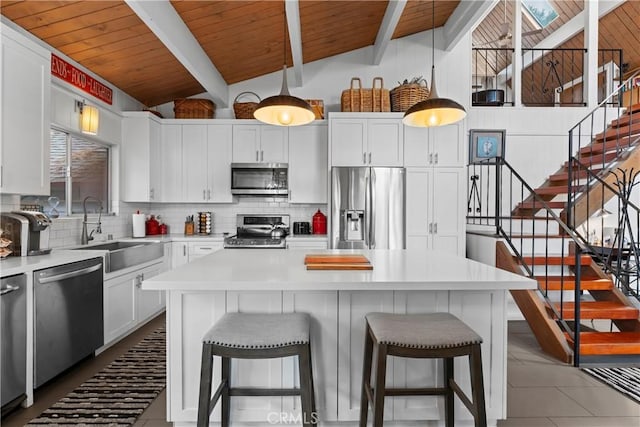 kitchen featuring stainless steel appliances, hanging light fixtures, a sink, and light countertops