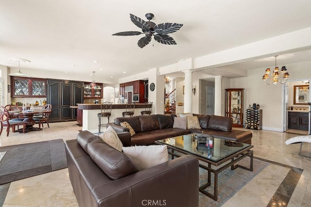 living room with ceiling fan with notable chandelier and decorative columns