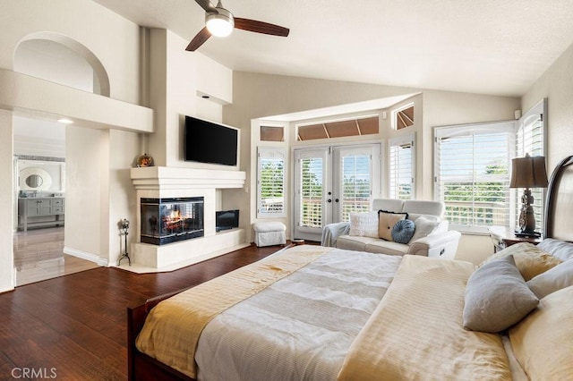 bedroom with access to outside, ceiling fan, high vaulted ceiling, a multi sided fireplace, and hardwood / wood-style floors