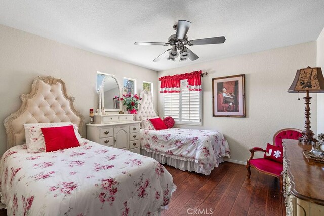 bedroom with a textured ceiling, ceiling fan, and dark wood-type flooring