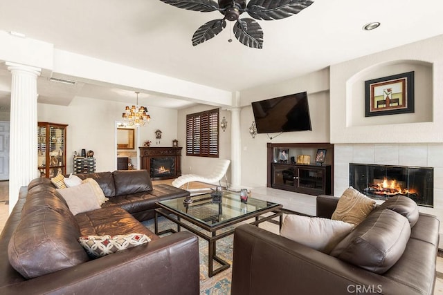 living room with a tiled fireplace and ceiling fan with notable chandelier